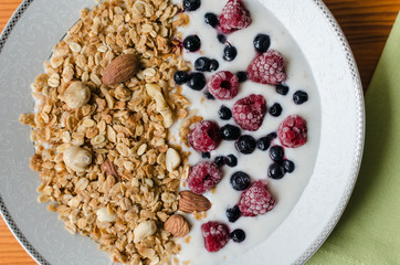 healthy breakfast, granola with yogurt and frozen raspberries and blueberries