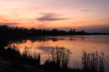 beautiful sunset is reflected in the water of a large lake in the forest © Chernobrovin