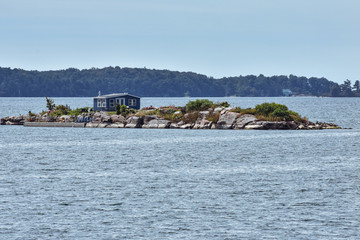 Blue Isolated cottage in a rocky island at the Thousand Islands. Ontario, Canada.