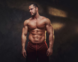 Fototapeta na wymiar Portrait of attractive muscular bodybuilder at dark photo studio with blinks of light.