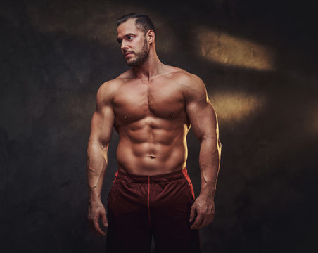 Portrait of attractive muscular bodybuilder at dark photo studio with blinks of light.