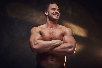 Fototapeta premium Portrait of attractive muscular bodybuilder at dark photo studio with blinks of light.