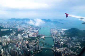 Aerial view of Hong Kong islands with skyscapers and industry from a flying airplane with wing