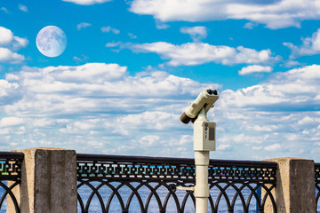 Paid tourist binocular telescope. Overview of the landscape and the moon in the clouds.