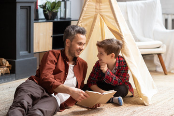 Laughing father and son read funny book together