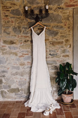 Vintage wedding dress is Hanging on the lamp on the stone wall and plant