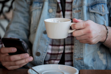 Close up of man hands holding smartphone. Watching him sms, messages, email in his cell phone cafe.