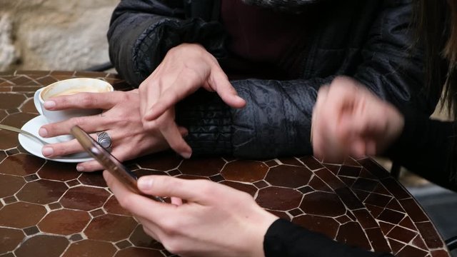 Women in cafe looking at a mobile phone, debating and planning