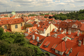 Fototapeta na wymiar Roofs of houses, buildings and St. Nicholas Church dome. Skyline and Schönborn Garden. View from Prague Castle (Pražský hrad).