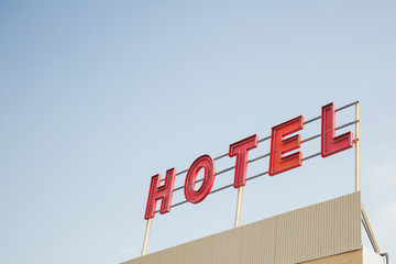 red inscription hotel on a roadside hotel building against a blue clear sky