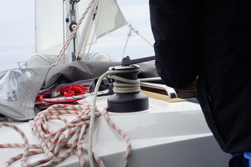 Close up of hands using a winch for the halyard rope on a sailboat