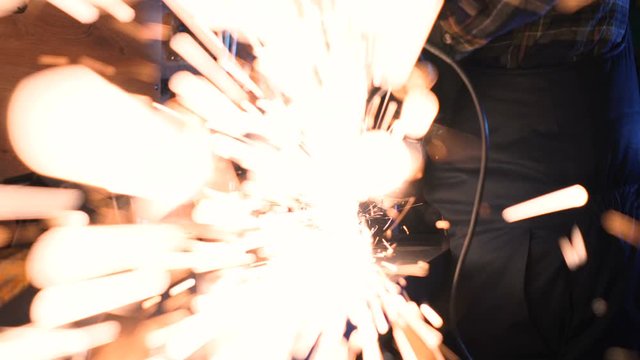 Close up footage of worker using ginder, sparks from ginder flying to the camera lens. Handheld shot.