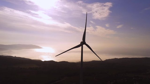 Wind turbine with Playa Barizo, Spain, on the background. Panning low to high camera shot.