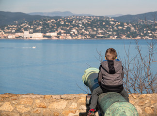 SAINT TROPEZ, FRANCE - DECEMBER 31, 2019: A child sitting on the cannon barrel on the citadel in Saint Tropez