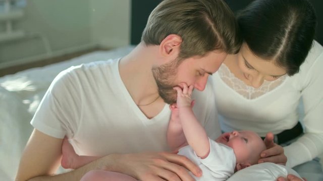 Happy family. Portrait of caucasian smiling mother father and newborn baby hugging at home. Parenthood Motherhood. Loving parents mom dad enjoying caring little child. healthy childcare, 4 K Slow-mo