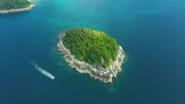 Nice rocks forested island, aerial panorama of Ko Pu against mountainous Phuket landscape on background. Deep tropical jungle thicket covering stony islend.Boat sailing. Aerial