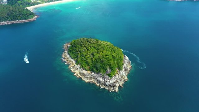 Nice rocks forested island, aerial panorama of Ko Pu against mountainous Phuket landscape on background. Deep tropical jungle thicket covering stony islend.Boat sailing. Aerial