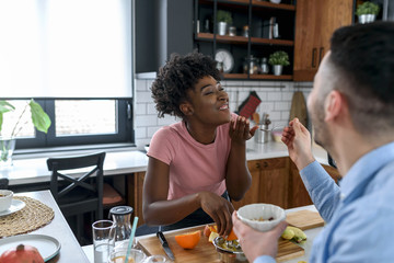 Young smiling interracial couple preparing healthy breakfast at home with lots of fruits. Healthy lifestyle.