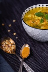 Homemade pea soup with turmeric and mint, white bowl on a dark background