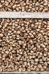 Background of stacked, dry chopped logs used for firewood.