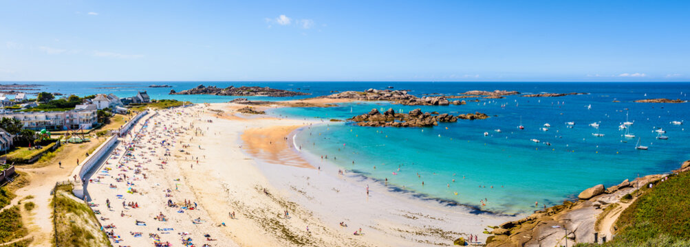 Aerial Panoramic View Over The White Sandy Beach Of Greve Blanche In Tregastel, Northern Brittany, France, On A Sunny Summer Day With Dozens Of People Sunbathing And Enjoying The Turquoise Sea.