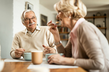 Happy senior man enjoying in breakfast with his wife at home.