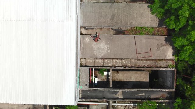 drone video birds eye view of a freerunner jumping over the rooftops of some abandoned buildings to escape