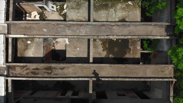 drone video birds eye view of a freerunner jumping over some abandoned buildings