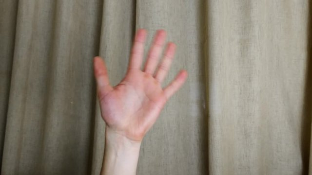 Waving final goodbye sign on a brown curtain background, closeup  