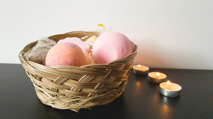 Wicker basket with a set for taking a bath: bath bombs, salt, soap. Lighted candles on the table. An atmosphere of relaxation and romance. Rest after a hard day
