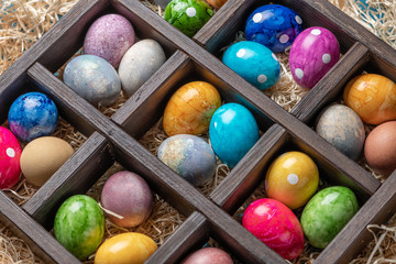 Different easter eggs in a box with straw