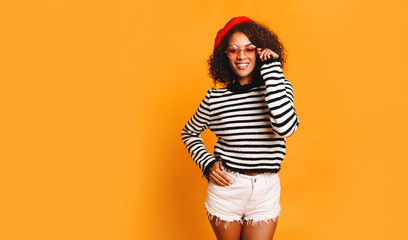 Portrait of happy young black woman laughing against yellow wall. Blissful lovable woman with...