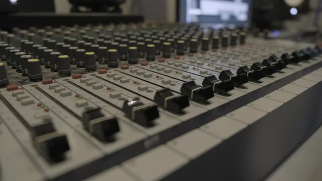 Audio sound mixer console in recording studio. fingers moving the sliders and turning the knobs