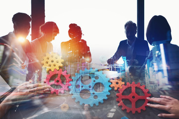 Businessmen that work together in office at night. Gears overlay. concept of teamwork and...