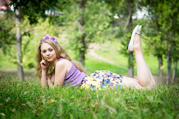 Blonde girl on the grass. Side view. Smiles.