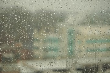 Raindrops on the glass window with blurry building on background, GA USA.