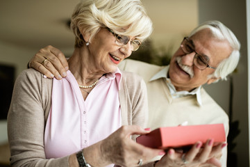 Happy senior woman receiving a gift from her husband.