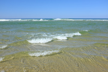 Sunny beach in La Teste-de-Buch, France with clear blue sky, turquoise sea and ocean waves. Summer holiday destination and scenic coastal landscape.