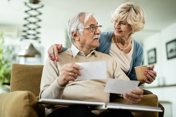 Obraz premium Senior couple communicating while looking at their photos at home.