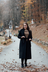 Fototapeta na wymiar Woman in coat in autumn park. Fall fashion. Outdoor portrait of pretty, young teen girl outdoors. Pretty woman posing in the park for the photographer. 