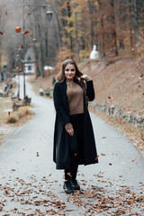 Fototapeta premium Woman in coat in autumn park. Fall fashion. Outdoor portrait of pretty, young teen girl outdoors. Pretty woman posing in the park for the photographer. 