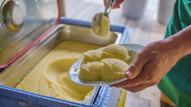 Slow motion of a man serving corn polenta on a plate at a traditional raft lunch