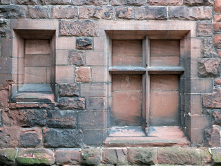 close up of the facade of an ancient worn red sandstone building with two blocked windows