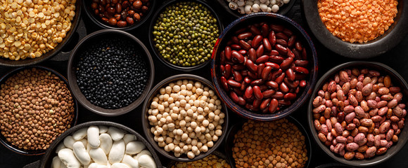 Legumes, a set consisting of different types of beans, lentils and peas on a black background, top...