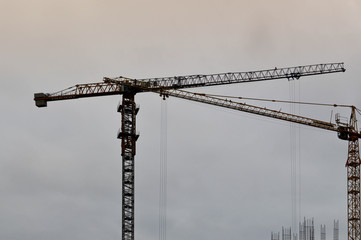 Large powerful construction cargo industrial crane on a construction site of new buildings and houses against the sky