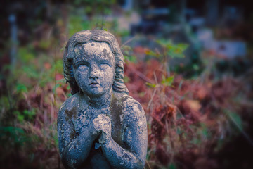 Fototapeta na wymiar Ancient statue of a praying angel on a blue sky. Retro filter.