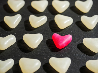 One red heart sweet candy between white jelly on a dark background. Concept love, the one, unique.