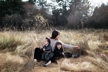Naklejka na ściany i meble woman with daughter and son on dry grass field. wheat field. family look. cute happy family