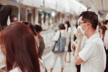 Middle aged Asian man wearing glasses and medical face mask with crowd,  Wuhan coronavirus, covid-19 virus, epidemic, pandemic,outbreak, quarantine,air pollution and health concept