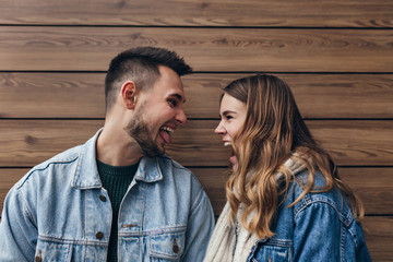 Funny european couple fooling around on wooden background. Indoor photo of curly blonde lady chilling with her boyfriend.